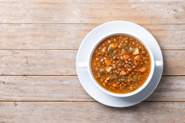 Soupe de lentilles avec des légumes dans un bol sur une table en bois