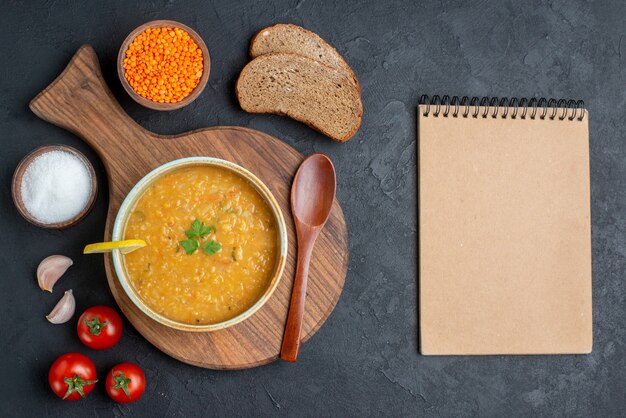 Soupe de lentilles vue de dessus avec lentilles crues au sel et pains de pain noir sur une surface sombre