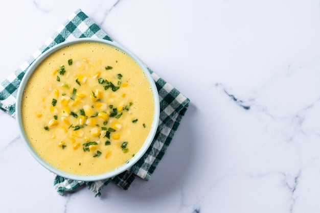 Soupe de maïs dans un bol vert sur du marbre blanc