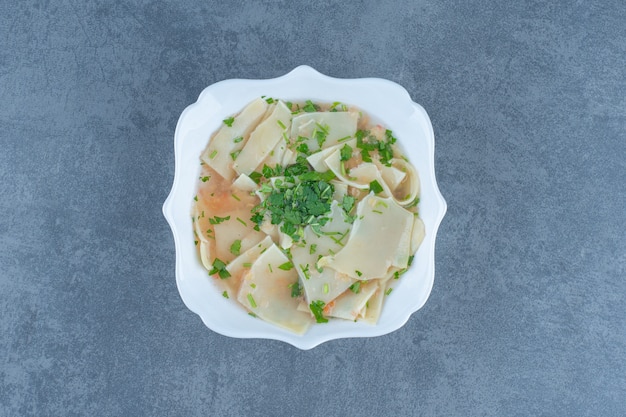 Soupe maison avec des pâtes dans un bol blanc.