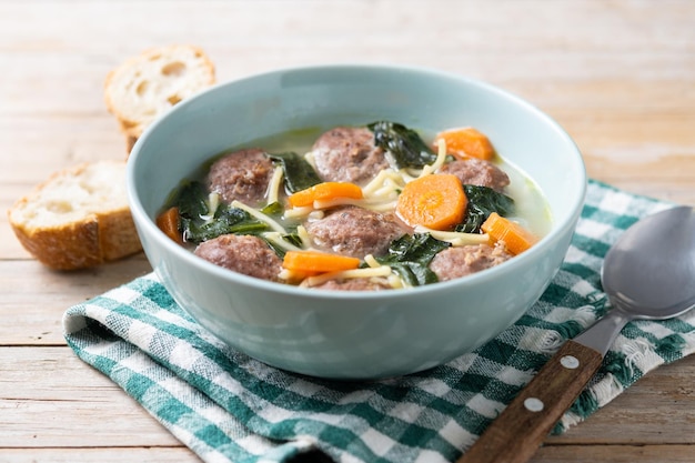 Soupe de mariage italienne avec des boulettes de viande et des épinards sur une table en bois