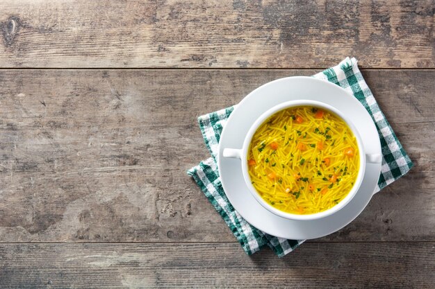 Soupe de nouilles au poulet dans un bol blanc sur une table en bois