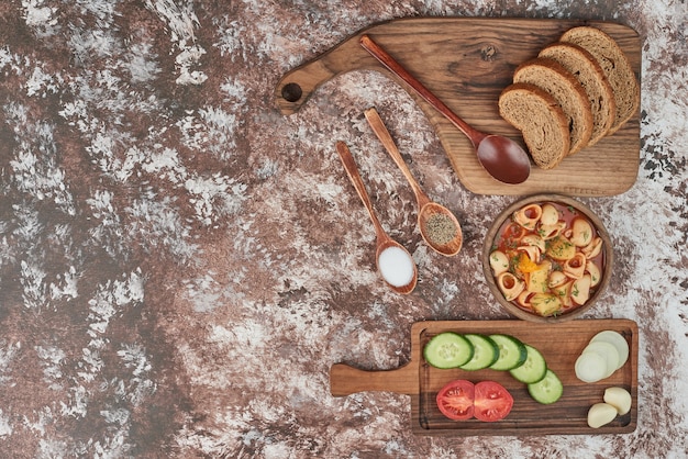 Soupe de pâtes avec salade de légumes et pain.