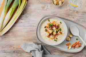 Photo gratuite soupe de poireaux au fromage avec croûtons et bacon dans un bol sur une table en bois vue sur le dessus