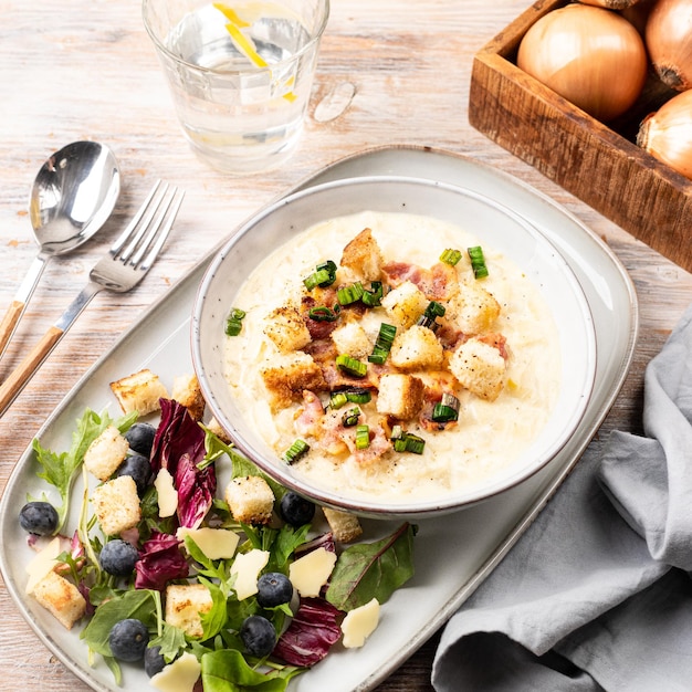 Photo gratuite soupe de poireaux au fromage avec croûtons de bacon et feuilles de laitue fraîches sur une table en bois soupe de poireaux au fromage