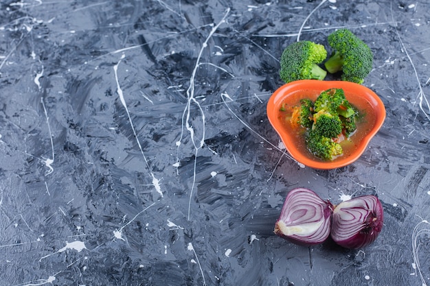 Soupe de poulet, brocoli et oignon, sur fond bleu.