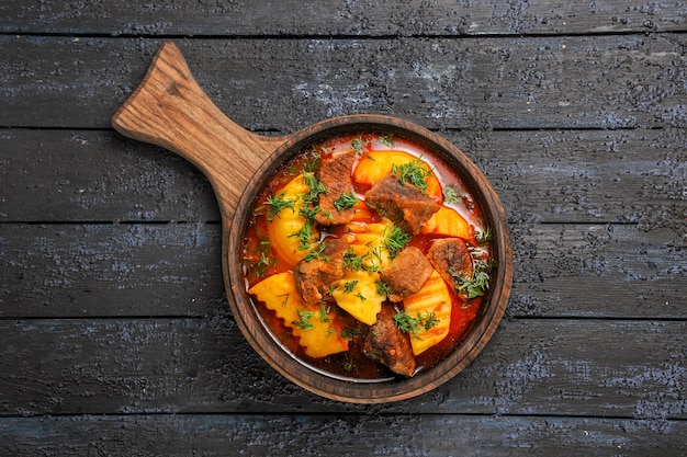 Photo gratuite soupe de sauce à la viande vue de dessus avec pommes de terre et légumes verts sur le bureau sombre