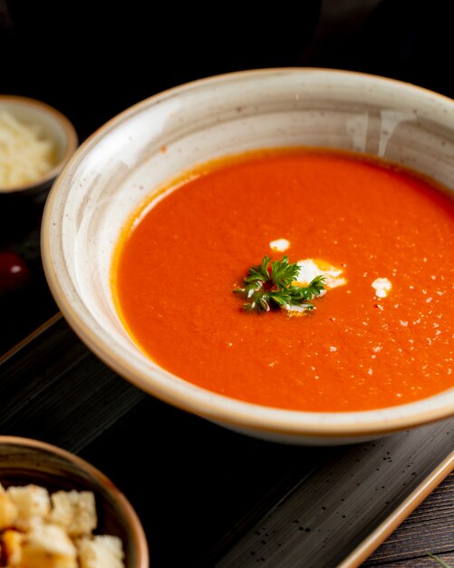 Soupe de tomate servie avec des légumes verts