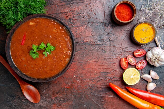 Soupe de tomates classique dans un bol brun et différentes épices ail citron sur table de couleurs mélangées