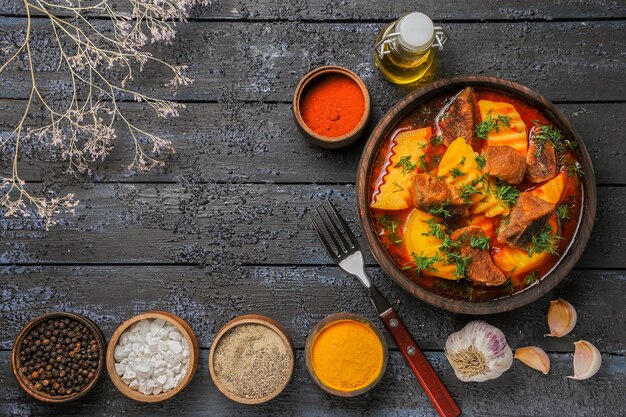 Soupe de viande vue de dessus avec pommes de terre et assaisonnements sur sol sombre