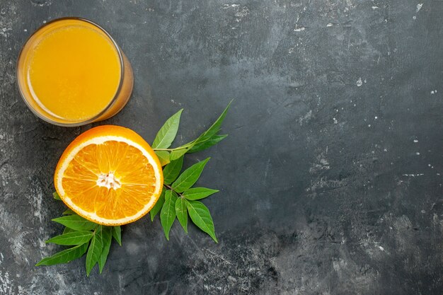 La source de vitamine a coupé des oranges fraîches et du jus avec des feuilles sur fond gris