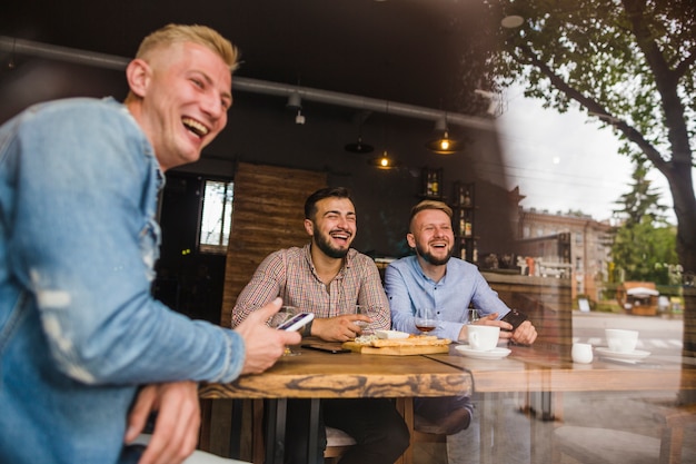 Photo gratuite souriant amis masculins bénéficiant dans le restaurant