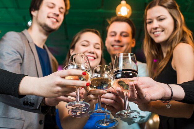 Souriant amis masculins et féminins griller des cocktails en soirée au bar