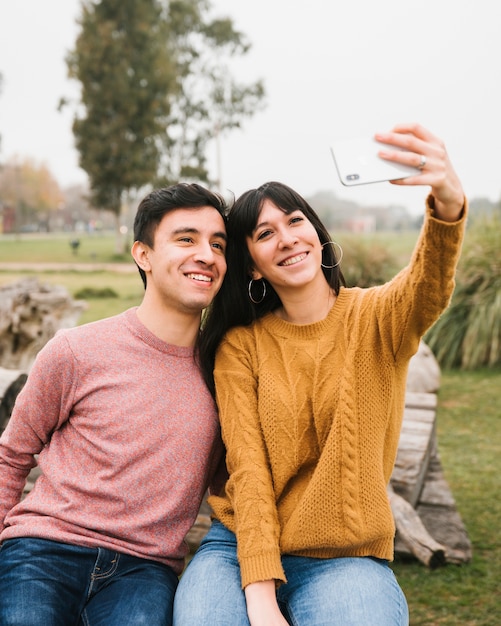 Souriant amis prenant selfie dans le parc