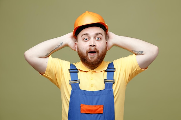 Souriant a attrapé la tête jeune constructeur homme en uniforme isolé sur fond vert