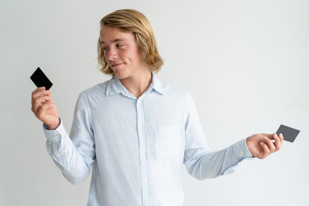 Souriant aux cheveux longs choisissant entre deux offres bancaires