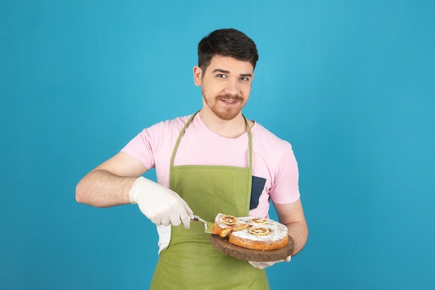 Souriant beau chef servant un gâteau frais.