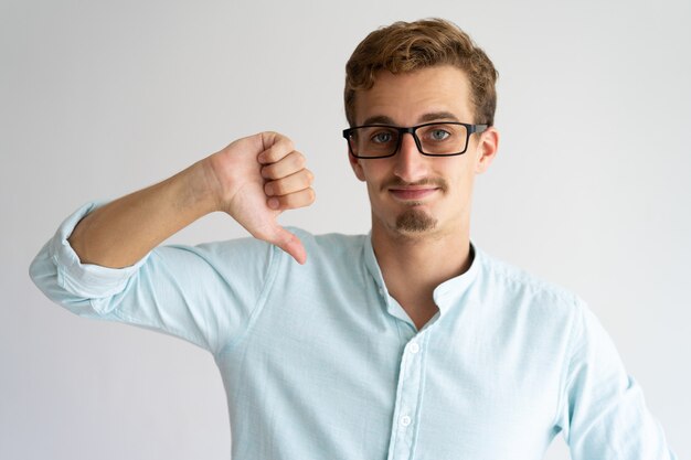 Souriant beau mec dans des lunettes exprimant sa désapprobation.