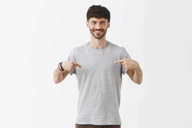 souriant beau mec posant contre le mur blanc