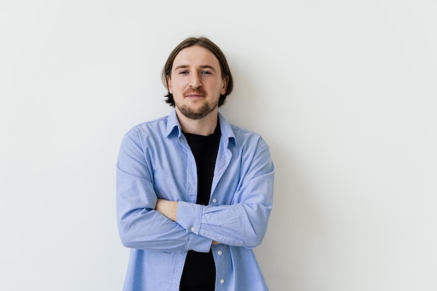 Souriant bel homme debout avec les bras croisés isolé sur fond gris