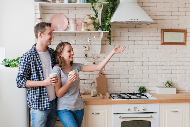 Souriant couple debout ensemble dans la cuisine