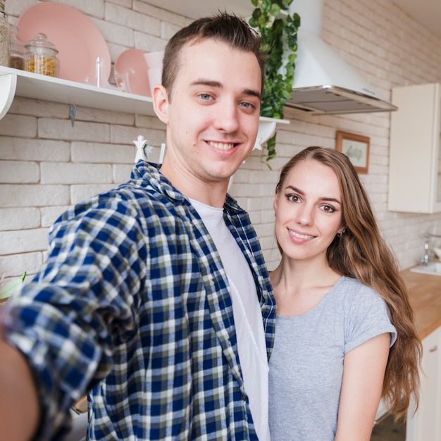 Souriant couple prenant selfie dans la cuisine