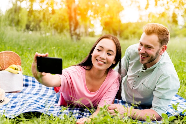 Souriant couple prenant selfie dans le parc