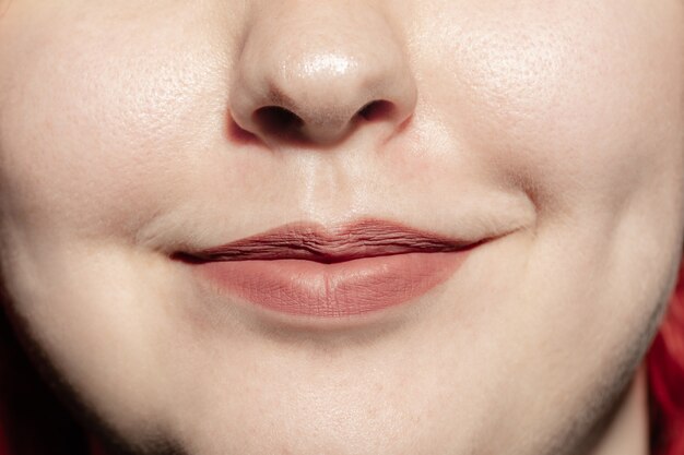 Souriant. Gros plan sur une bouche féminine avec un maquillage naturel des lèvres et une peau de joues bien entretenue