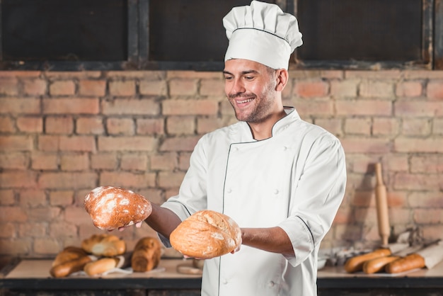 Photo gratuite souriant homme tenant des pains de pain frais cuits dans les mains