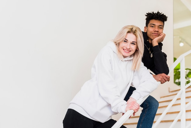 Souriant interracial jeune couple debout sur un escalier en regardant la caméra