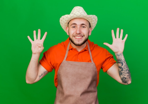 Souriant jardinier homme portant des gestes de chapeau de jardinage neuf avec les doigts