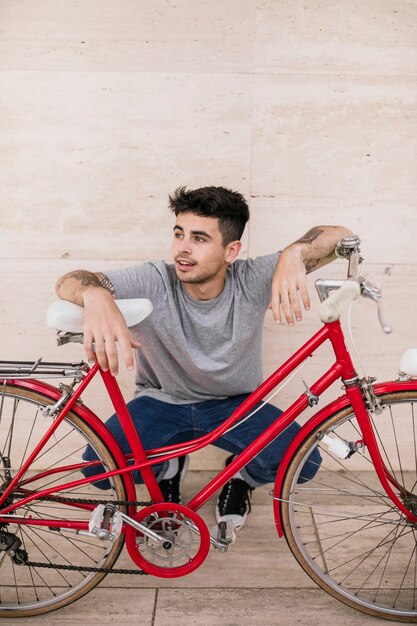 Souriant jeune adolescent assis au bord de la route avec vélo