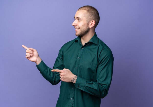 Souriant jeune beau mec portant des points de chemise verte sur le côté