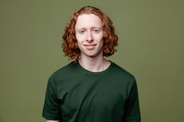 Souriant jeune beau mec portant un t-shirt vert isolé sur fond vert