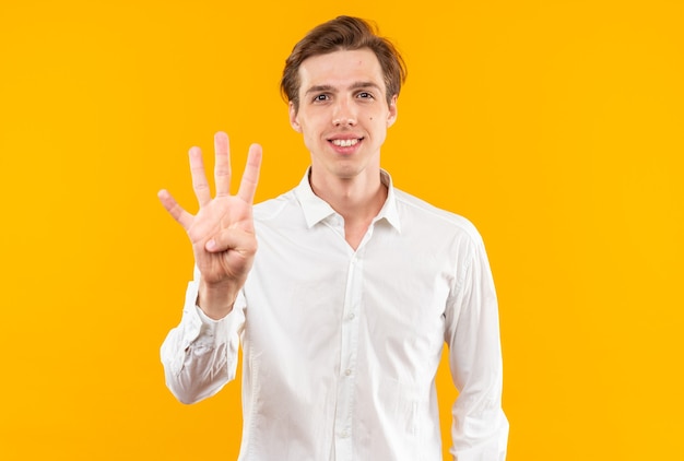 Souriant jeune beau mec vêtu d'une chemise blanche montrant quatre isolé sur un mur orange