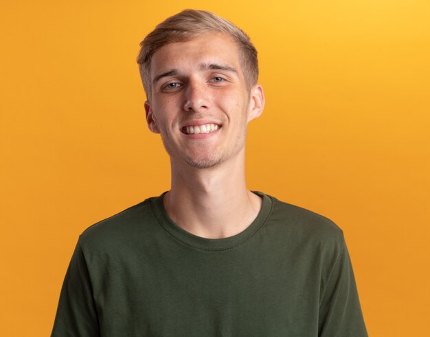 Souriant jeune beau mec vêtu d'une chemise verte isolée sur un mur jaune