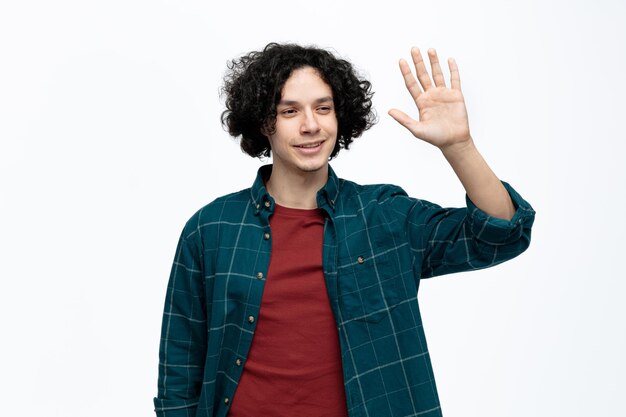 Souriant jeune bel homme regardant côté faisant salut geste isolé sur fond blanc