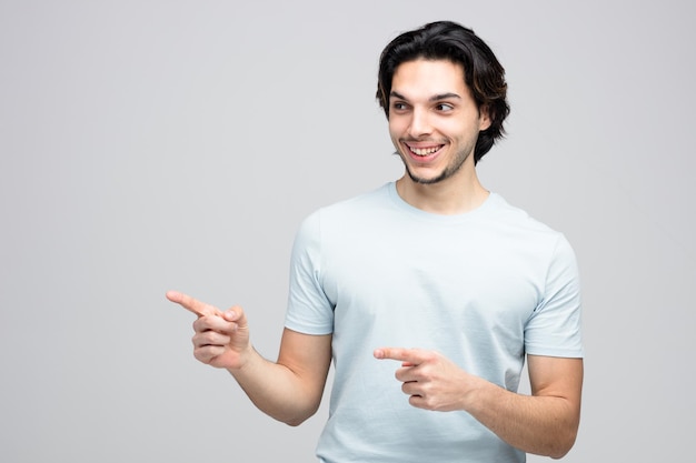 Souriant jeune bel homme regardant à côté vous montrant un geste à côté isolé sur fond blanc