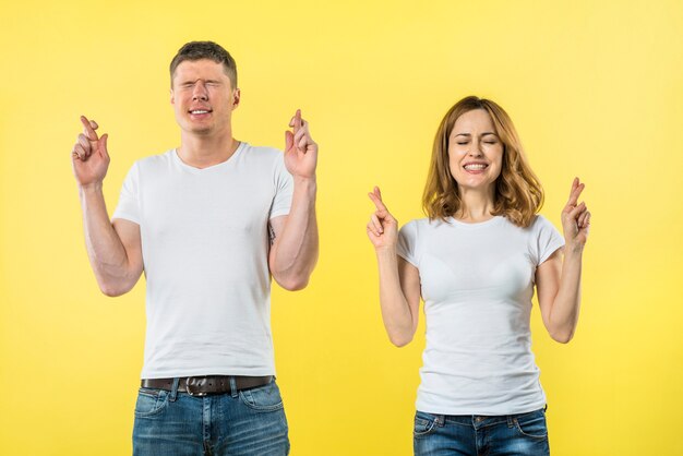 Souriant jeune couple croise les doigts en prévision de quelque chose d&#39;agréable