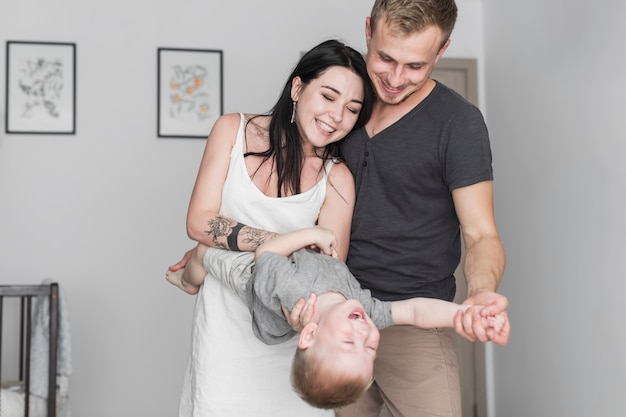 Photo gratuite souriant jeune couple jouant avec leur fils à la maison