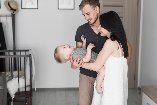 Souriant jeune couple jouant avec son fils à la maison