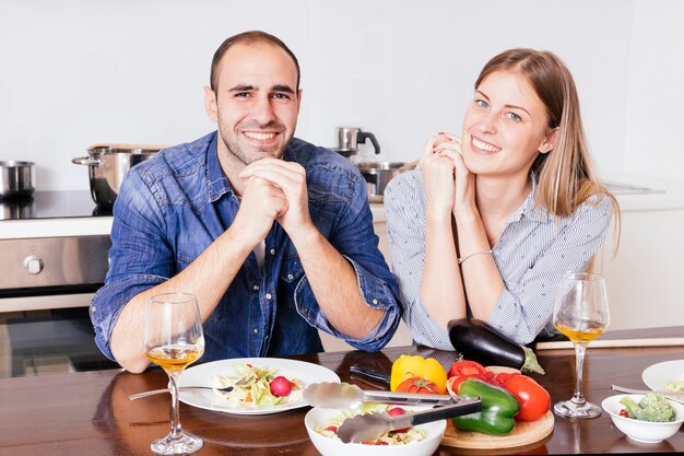 Photo gratuite souriant jeune couple prenant le petit déjeuner ensemble à la recherche de la caméra