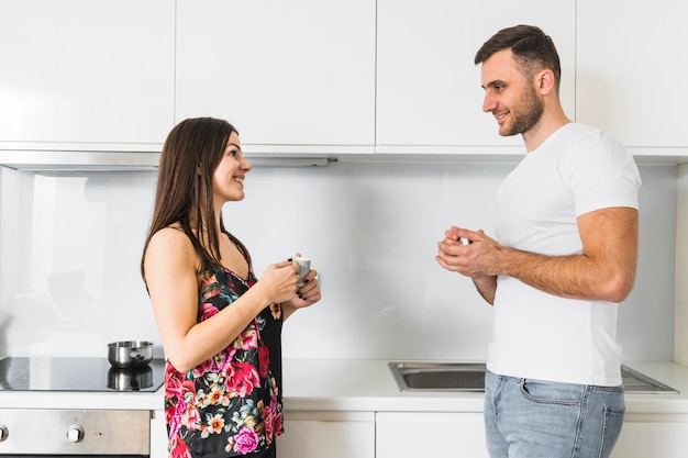 Souriant jeune couple tenant une tasse de café à la main se regardant