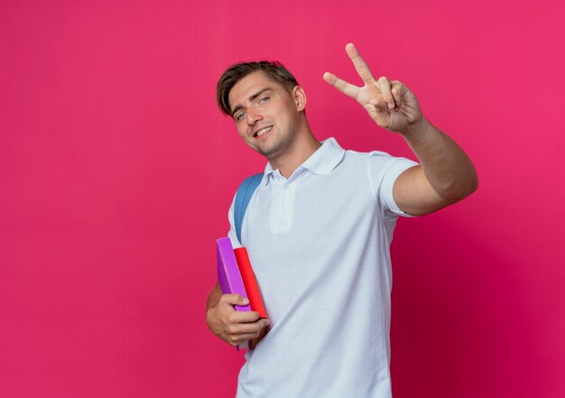 Souriant jeune étudiant beau mâle portant un sac à dos tenant des livres