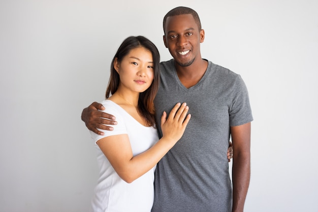 Souriant jeune homme africain étreignant sa petite amie asiatique.