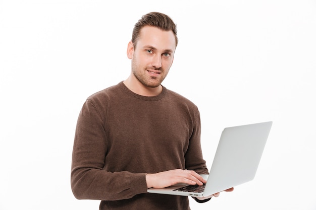 Souriant jeune homme à l'aide d'un ordinateur portable.