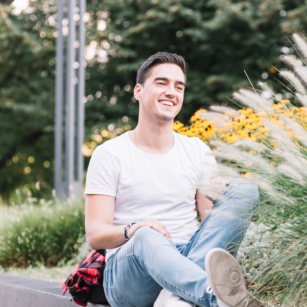 Souriant jeune homme assis dans le jardin