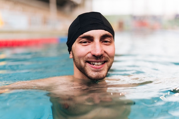 Photo gratuite souriant jeune homme au bord de la piscine