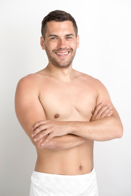 Souriant jeune homme avec un bras croisé en regardant la caméra