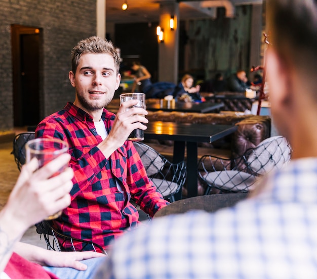 Souriant jeune homme buvant la bière avec ses amis dans un pub